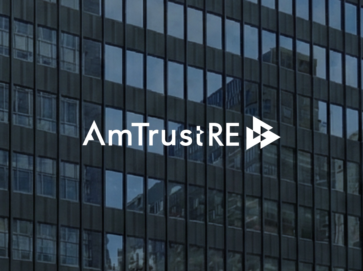 AmTrust RE logo overlaid on the glass window facade of the 260 Madison Avenue office building in New York City.